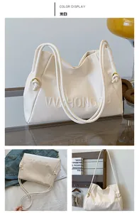 Detalle del bolso tote blanco crema con anillos metálicos y letras con relieve