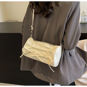 Detail of cream pillow bag showing pleated texture and elegant bow decorative accents