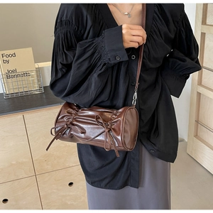 Brown ruched leather barrel crossbody bag with decorative bows and adjustable strap