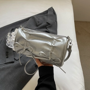 Detail of silver cylindrical bag with pleats and decorative bows held by hand