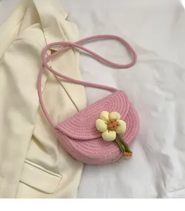 Close-up of pink woven saddle bag featuring a 3D yellow flower and handmade cotton texture