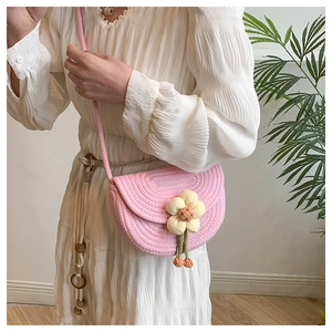 Close-up of pink woven cotton saddle bag with a decorative yellow flower and leaf charm