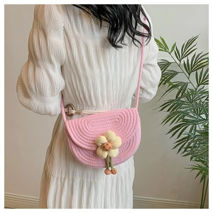 Pink woven saddle bag with yellow 3D flower detail shown on model's back