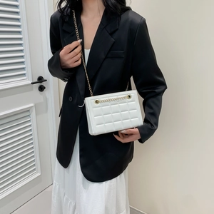 Sac à bandoulière blanc matelassé avec chaîne dorée porté par un mannequin chic