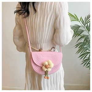 Detail of pink woven saddle bag featuring a 3D yellow fabric flower and wood ring accent