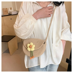 Detailed close-up of a woven beige saddle bag with a yellow flower ornament on a model
