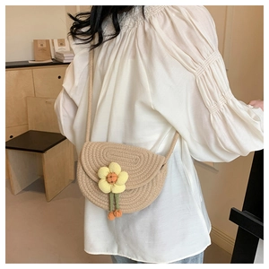 Detailed back view of a mini hand-woven saddle bag with a 3D floral accent on a model
