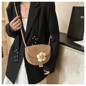 Detailed close-up of handmade woven straw crossbody bag with white 3D flower decoration