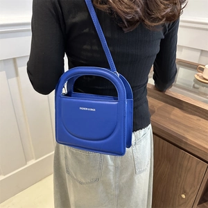 Royal blue faux leather crossbody square bag with top handle shown on a model