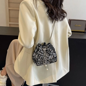 Mini sac seau à paillettes avec chaîne argentée et perles sur un blazer blanc