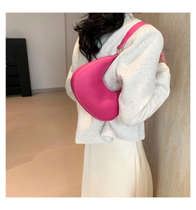 Detailed view of magenta crescent shoulder bag on a model wearing tweed jacket