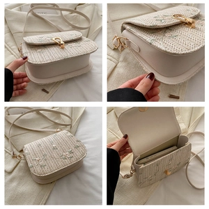 Detail of floral embroidery and golden horseshoe buckle on a woven straw saddle bag