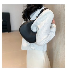 Side view of black matte leather crescent hobo bag with gold hardware on female model