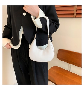Detail view of a white minimalist half-moon shoulder bag with smooth leather finish