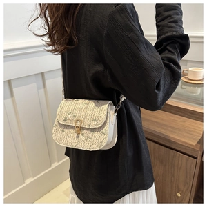 Close-up of woven crossbody bag featuring floral print cover and golden twist lock detail