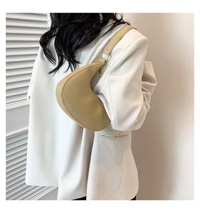 Detail of minimalist beige half-moon shoulder bag with sleek gold-tone zipper hardware