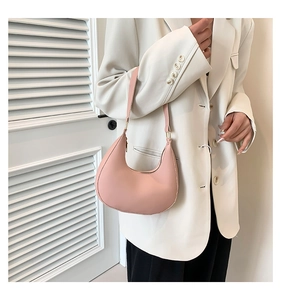 Close-up of pink crescent underarm bag in premium leather with gold hardware on a model