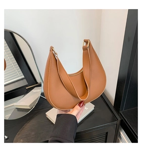 Detail view of a brown leather hobo bag with gold hardware and top zipper closure