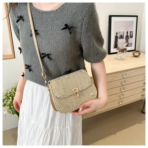 Detailed embroidery of pink and green flowers on beige straw shoulder bag texture
