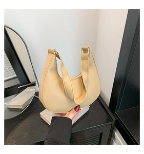 Close-up of minimalist beige crescent moon handbag with broad integrated top handle
