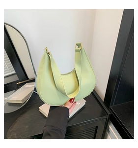 Close-up of pistachio green crescent bag with wide strap and gold metal buckle detail
