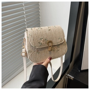 Detail of vintage woven bag with floral embroidery and gold metal snap buckle closure
