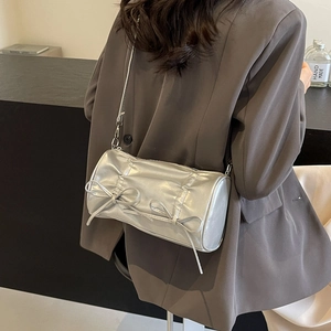 Chic silver pleated cylinder bag with bows being styled over a grey blazer