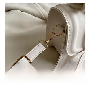 Close-up of golden metal lobster clasp and premium cream PU leather strap stitching