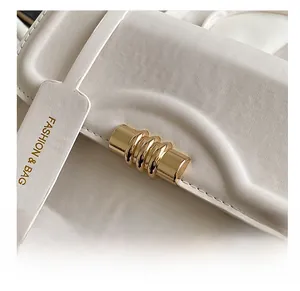 Close-up of beige leather bag featuring premium gold metal hardware and fashion logo tag