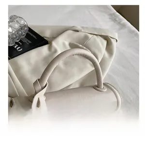 Detail showing high-quality stitching and elegant knotted handle on a beige leather bag
