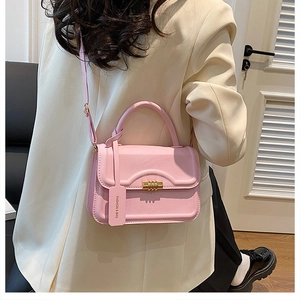 Detail der rosa Kunstleder-Handtasche mit goldener Zylinderschließe und schickem Anhänger