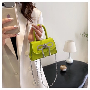 Detail of neon green mini crossbody bag featuring a sparkling rhinestone bow decoration