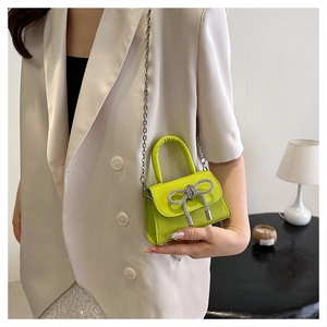 Détail du mini sac vert néon avec nœud en strass argenté et bandoulière chaîne