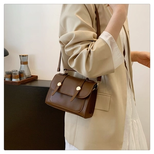 Detail of vintage brown leather crossbody bag styled with a beige suit for women