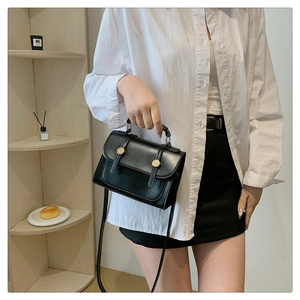 Detail of a black matte leather handbag with gold metal rings and a long shoulder strap