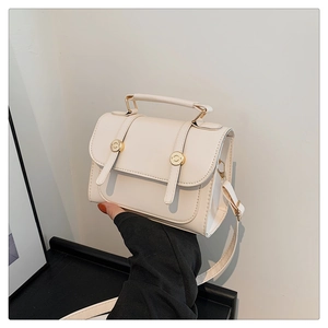 Detail of cream white mini crossbody bag with gold metal buckles and adjustable strap