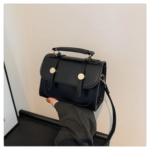 Detail of British style black PU leather bag with dual gold metal knobs and top handle