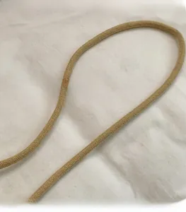 Detail of smooth khaki braided shoulder strap with tight woven texture on white fabric