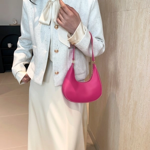 Minimalist rose red half-moon shoulder bag in smooth leather on a chic model
