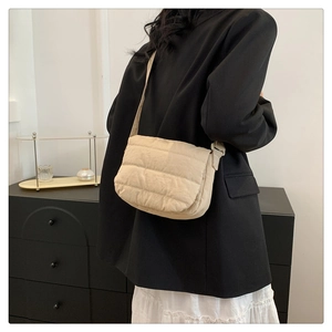 Close-up of a cream quilted crossbody bag featuring soft cloud texture and matching strap
