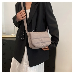 Detail of taupe quilted crossbody bag with horizontal stitching and fabric strap