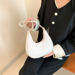 Minimalist white crescent shoulder bag in matte leather shown in a high-fashion studio shot