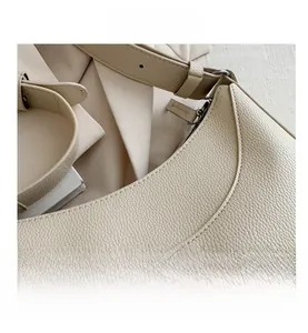 Close-up of beige lychee grain leather handbag showing fine stitching and metal zipper detail