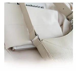 Detail of lychee textured cream shoulder bag showing silver ring strap connector