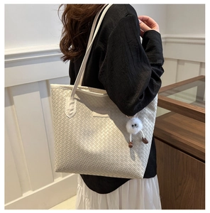Vue détaillée du sac cabas tissé avec pendentif monstre et doubles bandoulières