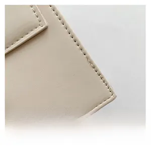 Macro shot of precise stitching and premium faux leather texture on cream square bag