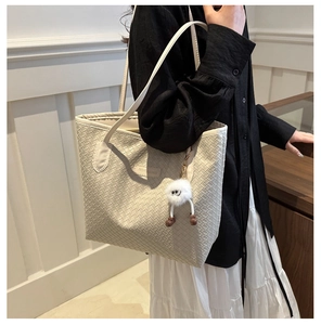 Détail du sac cabas en cuir tressé beige avec breloque monstre et étiquette mode