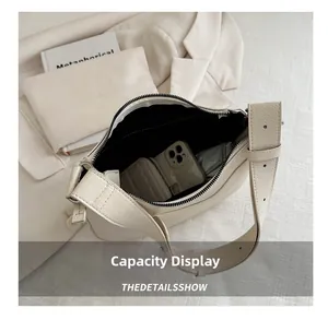 Internal capacity detail of minimalist beige crescent bag with smooth zipper closure