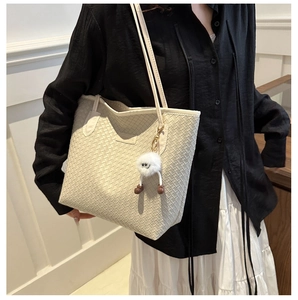 Sac cabas tissé beige chic avec un charm en peluche présenté dans un décor lifestyle