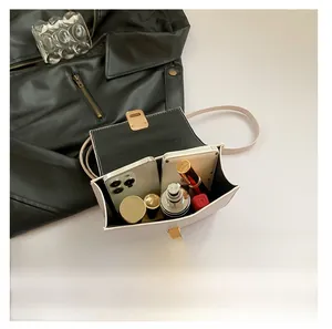 Top view showing interior capacity of the white leather handbag with phones and lipsticks